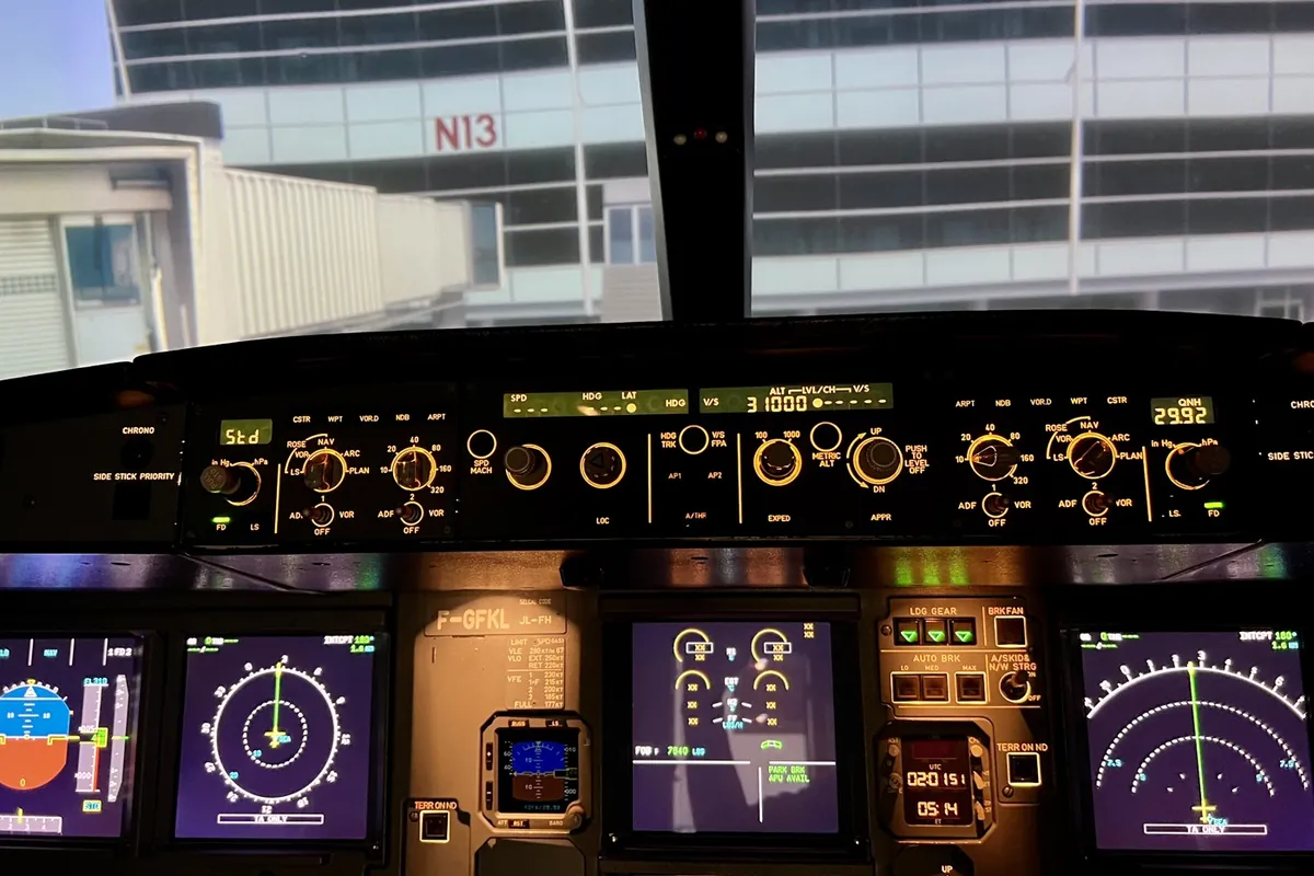 Close-up of an Airbus A-320 simulator instrument panel with an airport terminal in the visual display