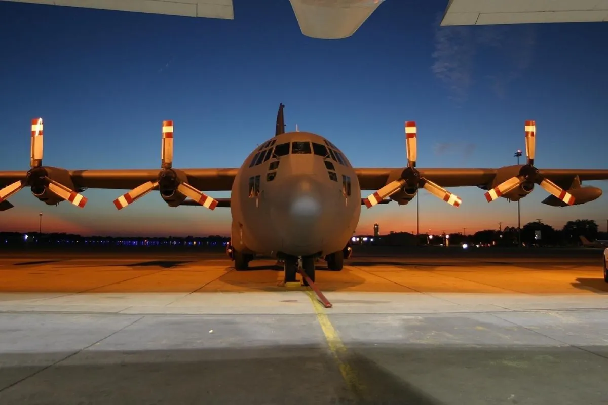C-130 Hercules military transport parked on a ramp at dusk