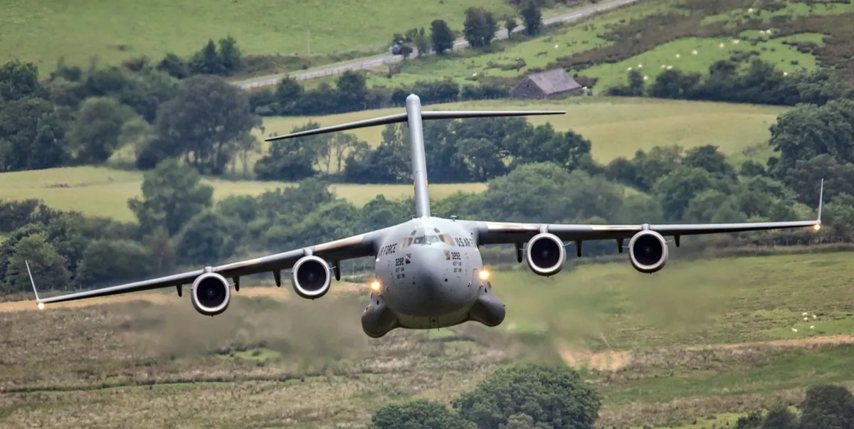 C-17 military jet transport flying low over green countryside
