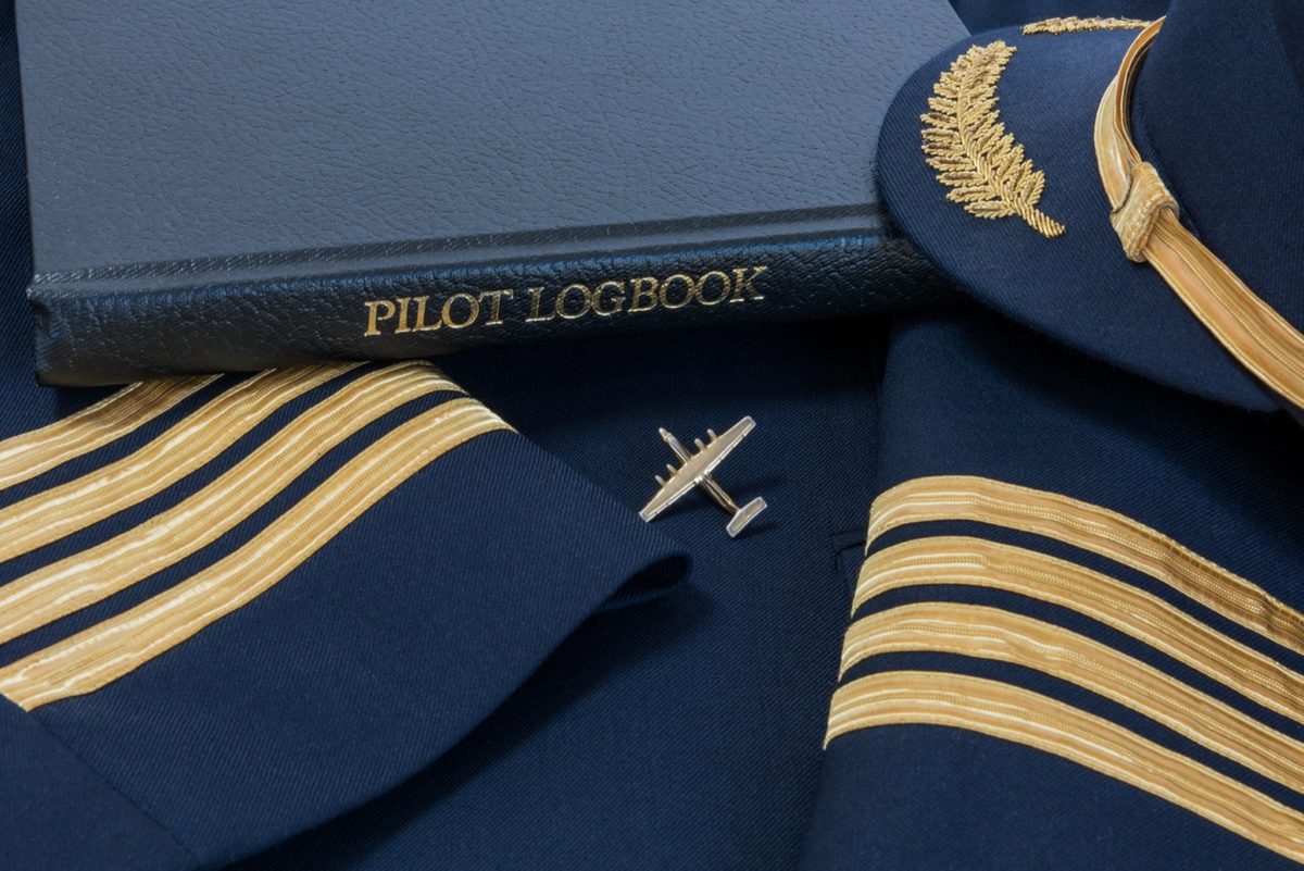 Navy blue pilot logbook with captain's stripes and a small airplane pin
